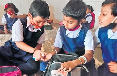 As schools reopened on Monday, Feb 28, 2022, after a gap of two years, a girl shares a sanitiser with her friend at Government High School, Unit-9, in Bhubaneswar (Photo I EPS, Biswanath Swain)