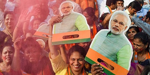 BJP supporters holding cutouts of PM Narendra Modi celebrate the party's performance in Assembly Polls. (Photo | PTI)