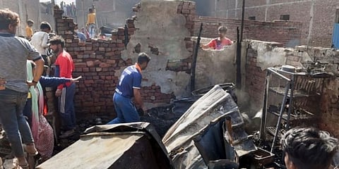 A man salvages belongings from the charred remains his house, after a fire broke out in shanties at Gokulpuri area, in New Delhi. (Photo | PTI)