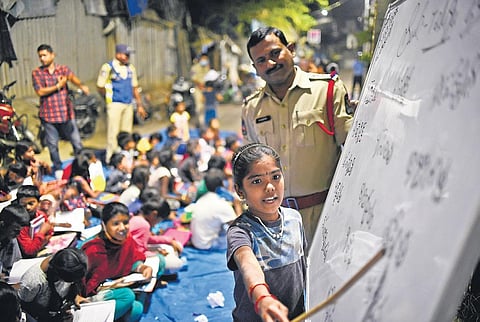 Inspector K Saidulu looks on as a child reads out from a whiteboard in Dasaram Basthi, Hyderabad | vinay Madapu