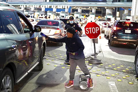 A Customs and Border Protection officer stands at the entrance to the San Ysidro Port of Entry as a boy sings for change among the waiting cars Wednesday, March 2, 2022. (Photo | AP)