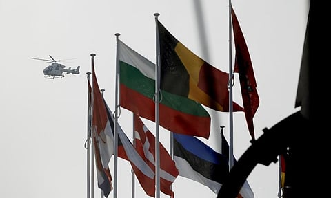 A police helicopter flies over NATO member country flags during a meeting of NATO defense ministers at NATO headquarters in Brussels. ( Photo | AP)