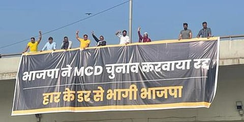 AAP workers hang a banner from a flyover on Thursday. (Photo| EPS)