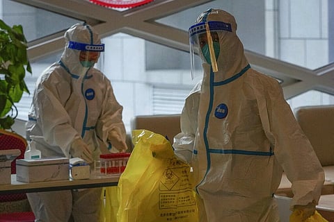 Health workers wearing protective suits collect COVID-19 test samples at a hotel used for people to stay during a period of health quarantine Sunday, March 20, 2022. (Photo | AP)
