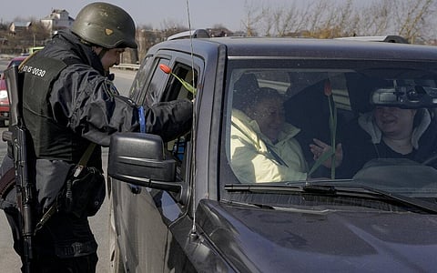 A Ukrainian police officer offer tulips to female travelers at a checkpoint on the outskirts of Kyiv, Ukraine, Sunday, March 20, 2022. (Photo | AP)