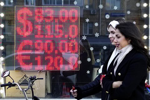 People walk past a currency exchange office screen displaying the exchange rates of U.S. Dollar and Euro to Russian Rubles in Moscow's downtown. (Photo | AP)