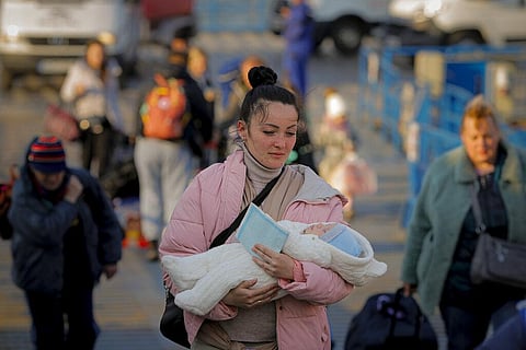 A refugee fleeing the war from neighbouring Ukraine walks with a baby in her arms after crossing the border by ferry at the Isaccea-Orlivka border crossing in Romania. (Photo | AP)