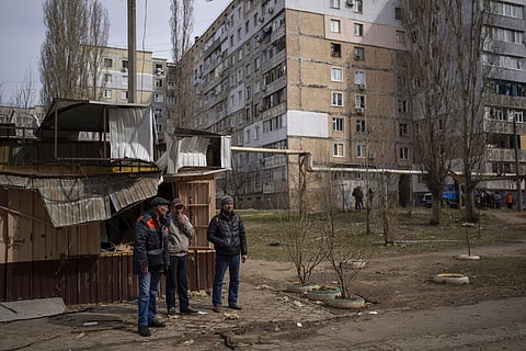 Men standing in front of damaged kiosks look at the damaged buildings after a Russian attack on the previous night in the residential area of Mikolaiv. (Photo | AP)