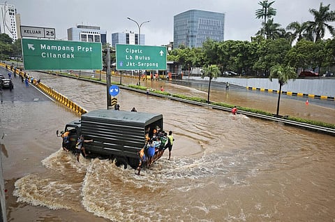 A military truck drives through the water on a flooded toll road following heavy rains in Jakarta, Indonesia, Saturday