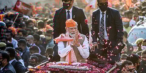 Prime Minister Narendra Modi greets supporters during a roadshow for the seventh and last phase of UP Assembly elections.(Photo | PTI)