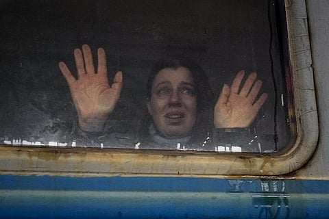 A woman looks toward relatives and presses her palms against a window of a Lviv bound train, on the platform in Kyiv, Ukraine, Thursday, March 3, 2022. (AP Photo)