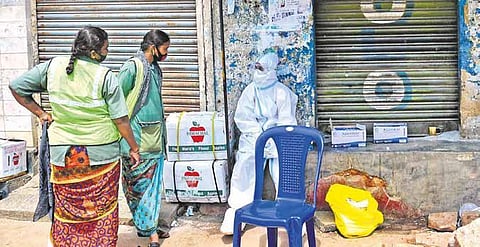 A health worker wearing a PPE kit speaks to pourakarmikas at Kalasipalya in Bengaluru (Photo | EPS, Shriram BN)