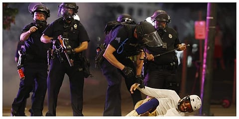 Denver Police Department officers clear a man who fell to the street after they used tear gas and rubber bullets to disperse a protest outside the State Capitol over the death of George Floyd, in 2020