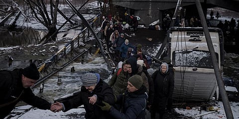 Ukrainians cross an improvised path under a destroyed bridge while fleeing Irpin, in the outskirts of Kyiv, Ukraine, Tuesday, March 8, 2022. (Photo | AP)