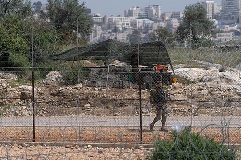 An Israeli soldier guards an opening in Israel's West Bank separation barrier that was reinforced with barbed wire to prevent Palestinians from crossing into Israel. ( Photo | AP)