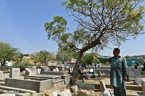 A man points to where his father's grave used to be at the Korangi graveyard in Karachi. (Photo | AFP)