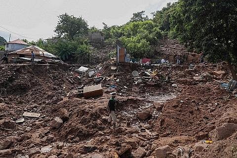 A man walks past the remains of a house at KwaNdengezi township outside Durban, South Africa, April 15, 2022. (Photo | AFP)