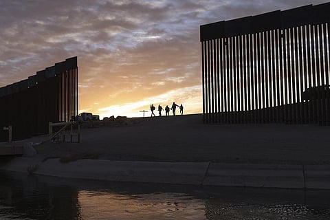 migrant families from Brazil passes through a gap in the border wall to reach the United States after crossing from Mexico. (Photo | AP)