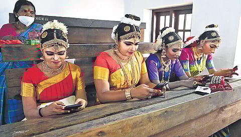 Bharatanatyam contestants check their mobile phones as they wait for their turn to perform | Vincent Pulickal