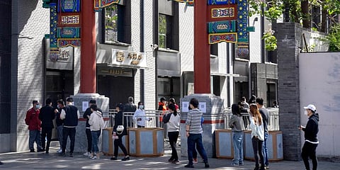 People wearing face masks line up for coronavirus tests in a neighborhood in the Dongcheng district of Beijing. (Photo | AP)