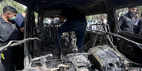 Pakistani investigators examine a burned van at the site of explosion in Karachi. (Photo | AP)