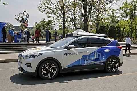 A Baidu Apollo Robotaxi passes its customer service counter setup at the Shougang Park in Beijing. (File Photo | AP)
