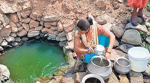 A woman collecting water from a pit | Express