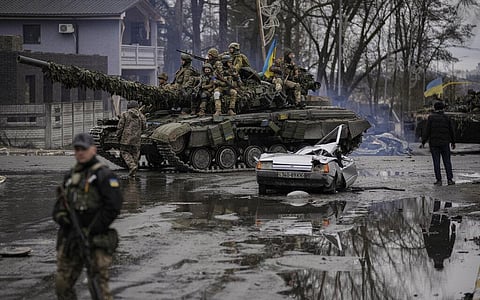 A man stands next to a civilian vehicle that was destroyed during fighting between Ukrainian and Russian forces that still contains the dead body of the driver. (Photo | AP)