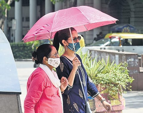 Women use umbrellas to protect themselves from the sun on a hot summer day on Rajpath on Sunday | Parveen Negi