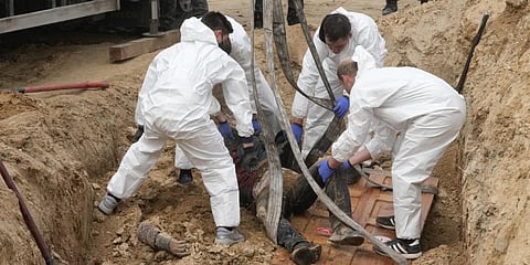 Men wearing protective gear exhume the bodies of killed civilians in Bucha, on the outskirts of Kyiv, Ukraine, Friday, April 8, 2022. (Photo | AP)