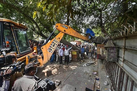 A bulldozer razes an illegal structure during an anti-encroachment drive by the MCD at the New Friends Colony, in New Delhi. (Photo | PTI)