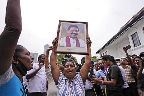 Sri Lankan government supporters shout slogans holding a portrait of prime minister Mahinda Rajapaksa outside his official residence in Colombo. (Photo | AP)