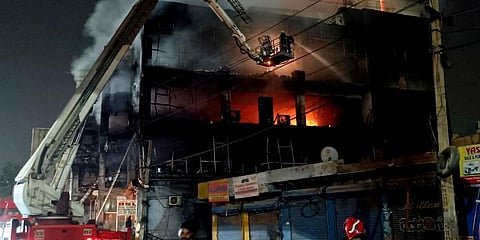 Fire officials try to douse a fire in a four storied building, in New Delhi. (Photo | AP)