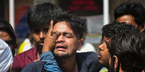 Family members of the missing people who are unsure about their whereabouts react after a massive fire at an office building near the Mundka Metro Station. (Photo | PTI)