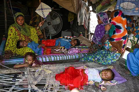 In this picture taken on May 11, 2022, a woman fans her children amid a power cut during a heatwave in Jacobabad, in the southern Sindh province. (AFP)