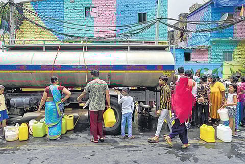 Residents wait in line to collect drinking water from a tanker at Laxmi Bai Nagar| pti