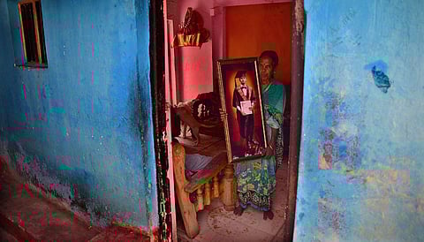 A woman proudly holds a portrait of her grandson who completed MSc in biotechnology at workers’ quarters of Bharath Gold Mine Limited in KGF. (Photo | Shriram BN, EPS)