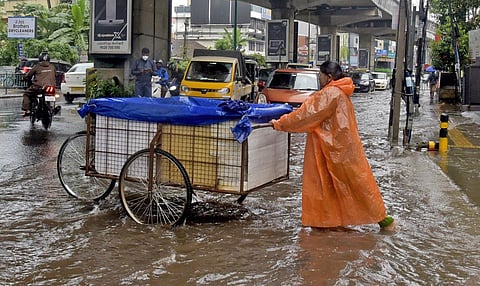 A cleaning staffer of Kochi corporation pushing a cart through a flooded road. (Photo | A Sanesh, EPS)