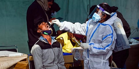 A health worker collects swab samples of passengers to conduct COVID-19 test in New Delhi. (Photo | PTI)