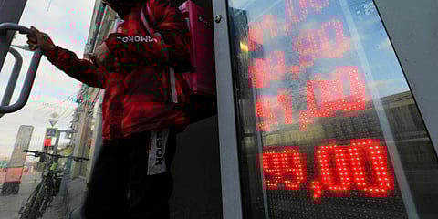A food delivery man leaves an exchange office with screen showing the currency exchange rates of U.S. Dollar and Euro to Russian Rubles in Moscow. (Photo | AP)