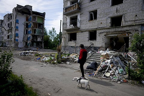 A man walks a dog in front of a building ruined by shelling in Borodyanka, on the outskirts of Kyiv, Ukraine, Wednesday, May 25, 2022. (Photo | AP)