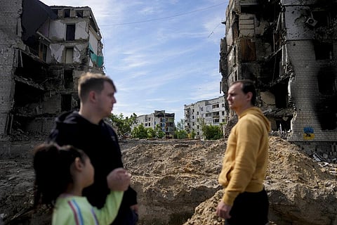People stand in front of a building damaged by shelling in Borodyanka, on the outskirts of Kyiv, Ukraine, Wednesday, May 25, 2022. (Photo | AP)