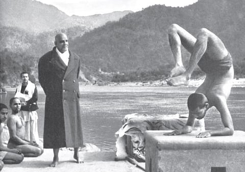 Swami Sivananda observes Swami Vishnudevananda doing the scorpion pose