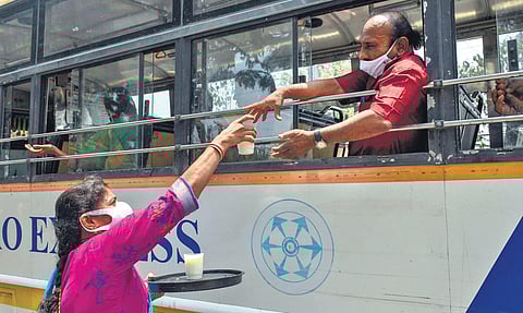 A woman distributes buttermilk to commuters in an RTC bus on a hot, sunny day in Vijayawada on Tuesday. (Photo | EPS, Prasant Madugula)