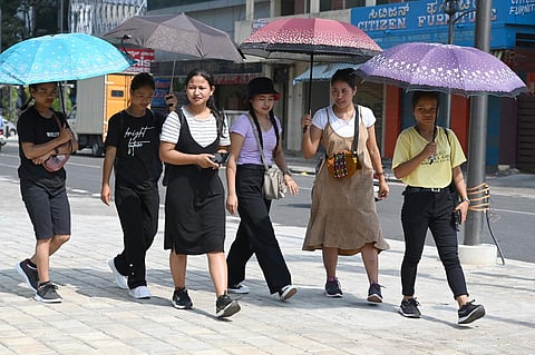 Medical students use umbellas to protect themselves from the heat, at Shivaginagar in Bengaluru. (Photo | Nagaraja Gadekal, EPS)