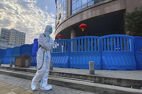 A worker in protectively overalls and carrying disinfecting equipment walks outside the Wuhan Central Hospital, China. (File Photo | AP)