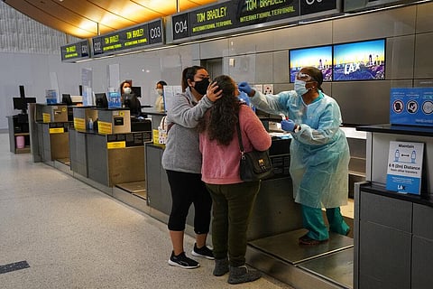 Licensed vocational nurse Caren Williams, right, collects a nasal swab sample from a traveler at a COVID-19 testing site at the Los Angeles International Airport in Los Angeles. (File Photo | AP)