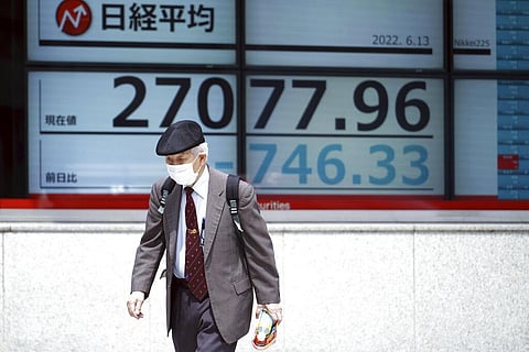 A man wearing a protective mask walks in front of an electronic stock board showing Japan's Nikkei 225 index at a securities firm Monday, June 13, 2022, in Tokyo.(Photo | AP)