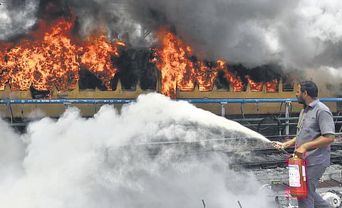 A railway staffer extinguishes the fire on a train set afire at Secunderabad station on Friday | VINAY MADAPU