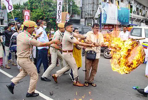 Police personnel try to snatch a burning effigy from a protester during a protest against the Agnipath scheme, in Kolkata. (Photo | PTI)